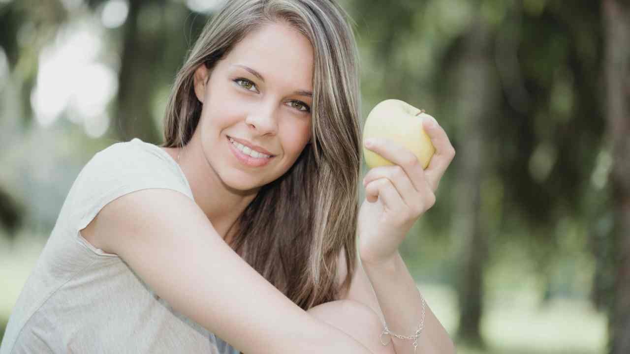 Ragazza sorridente con la mela