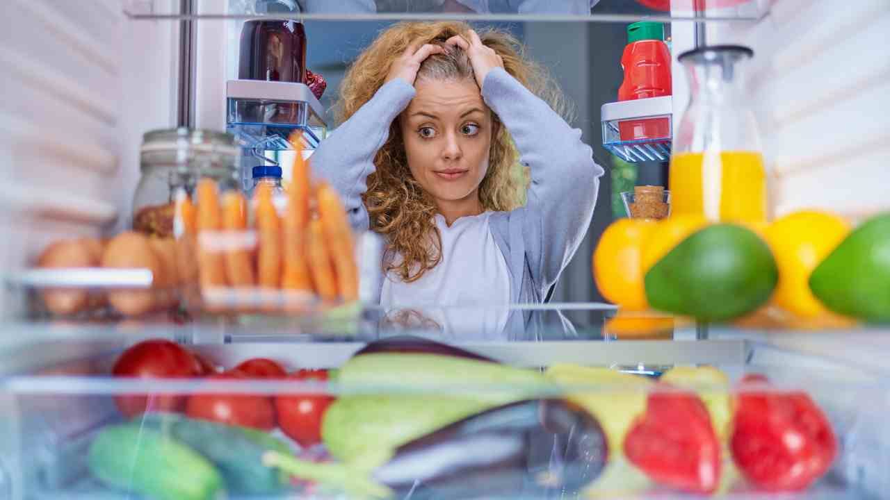 Ragazza guarda il cibo nel frigo