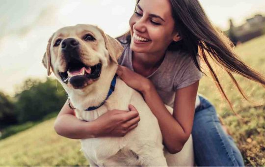 Giovane donna con il suo cane sorridente: soffre il solletico?