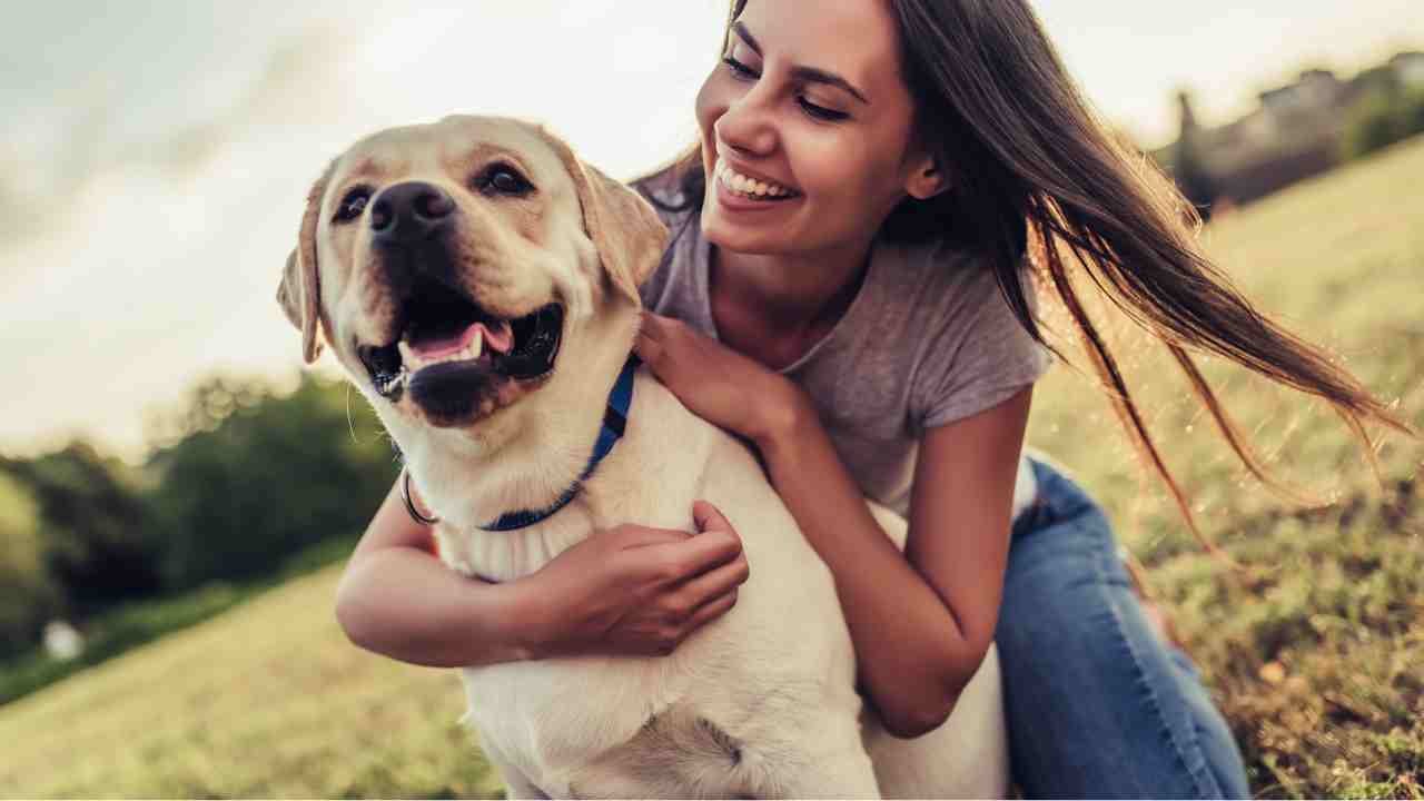 Giovane donna con il suo cane sorridente: soffre il solletico?