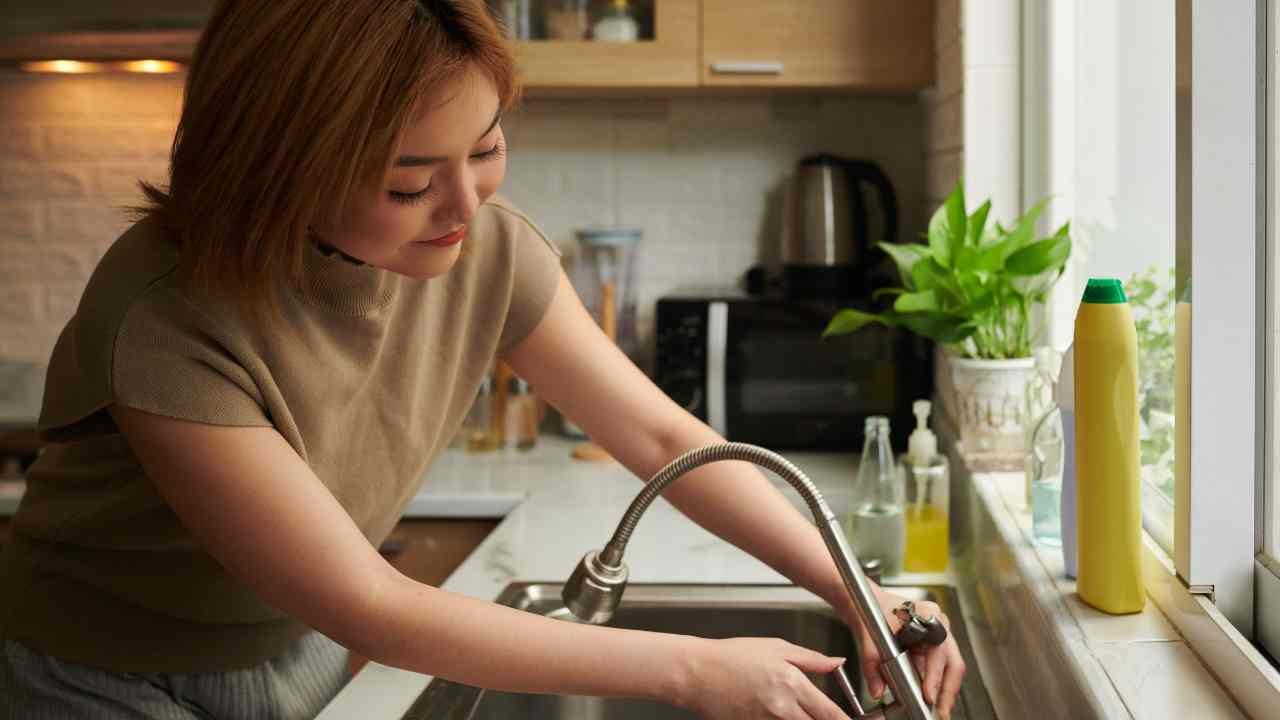 Donna ripara il rubinetto che perde acqua